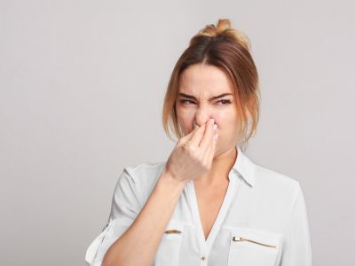 Woman pinching her nose, reacting to a foul odor, illustrating signs of gas leaks and the importance of recognizing unusual smells for household safety.